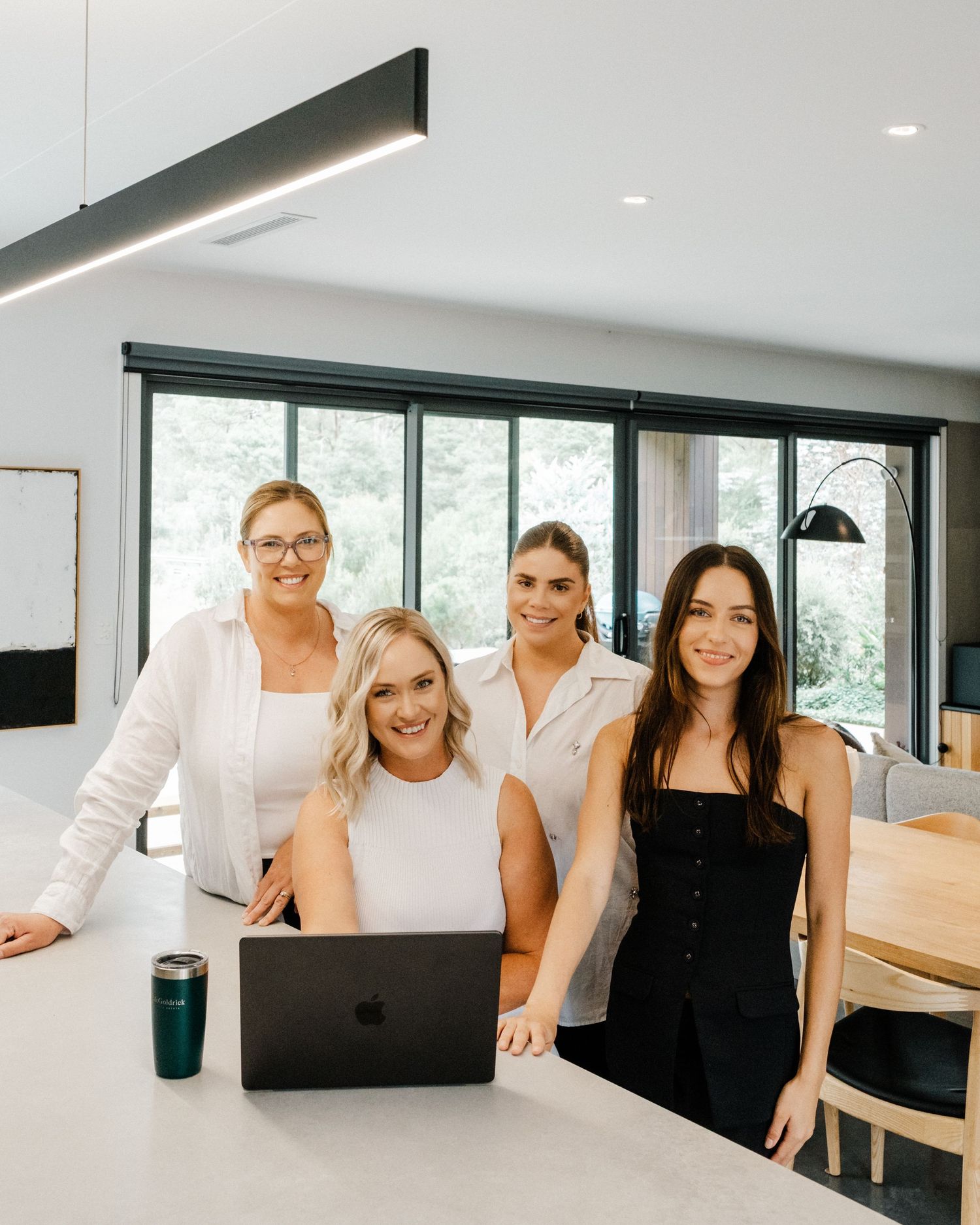 Four professionals in white and black attire working together in a modern office space.