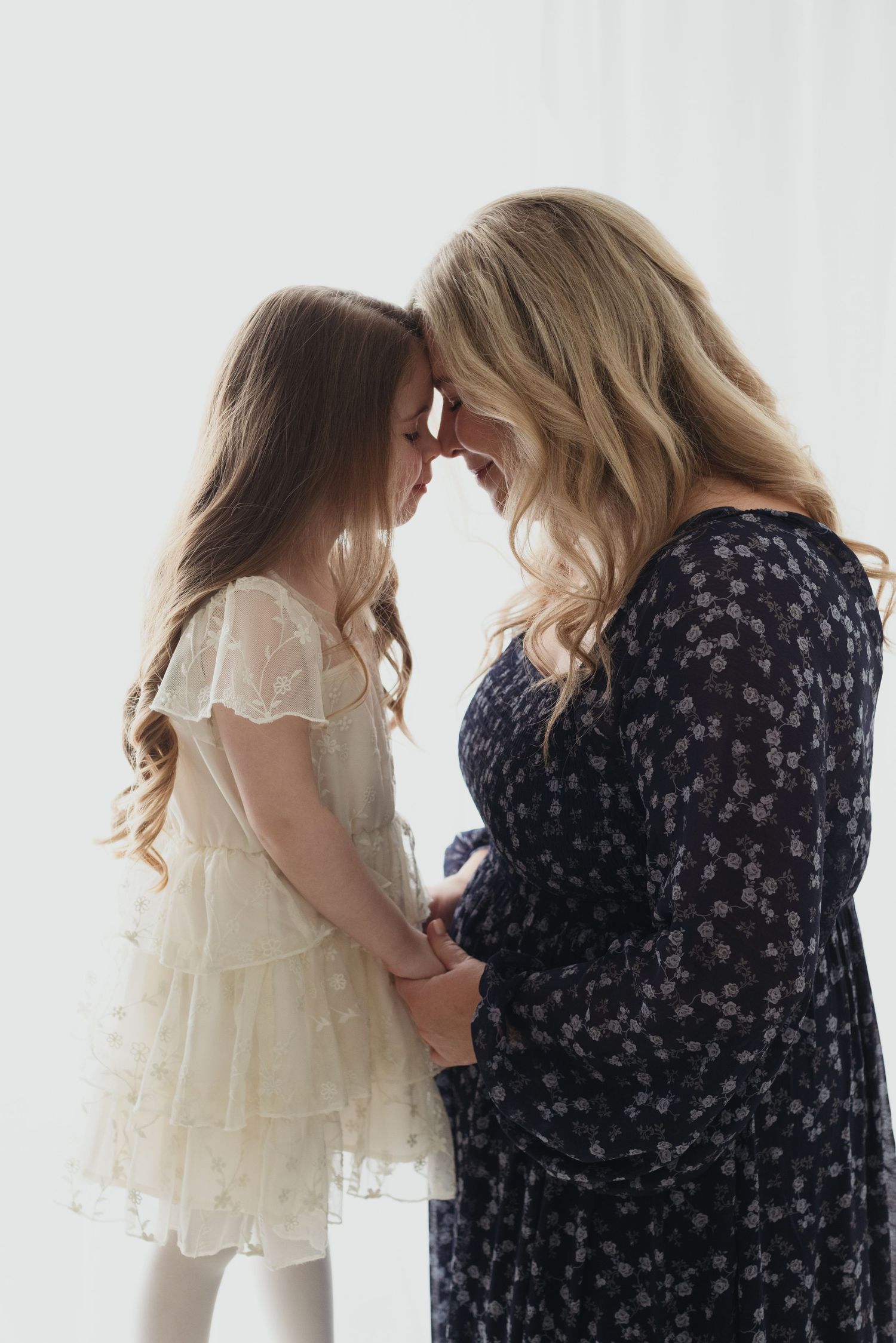 A tender moment shared between two people in contrasting dresses - one in white lace and one in navy floral print.