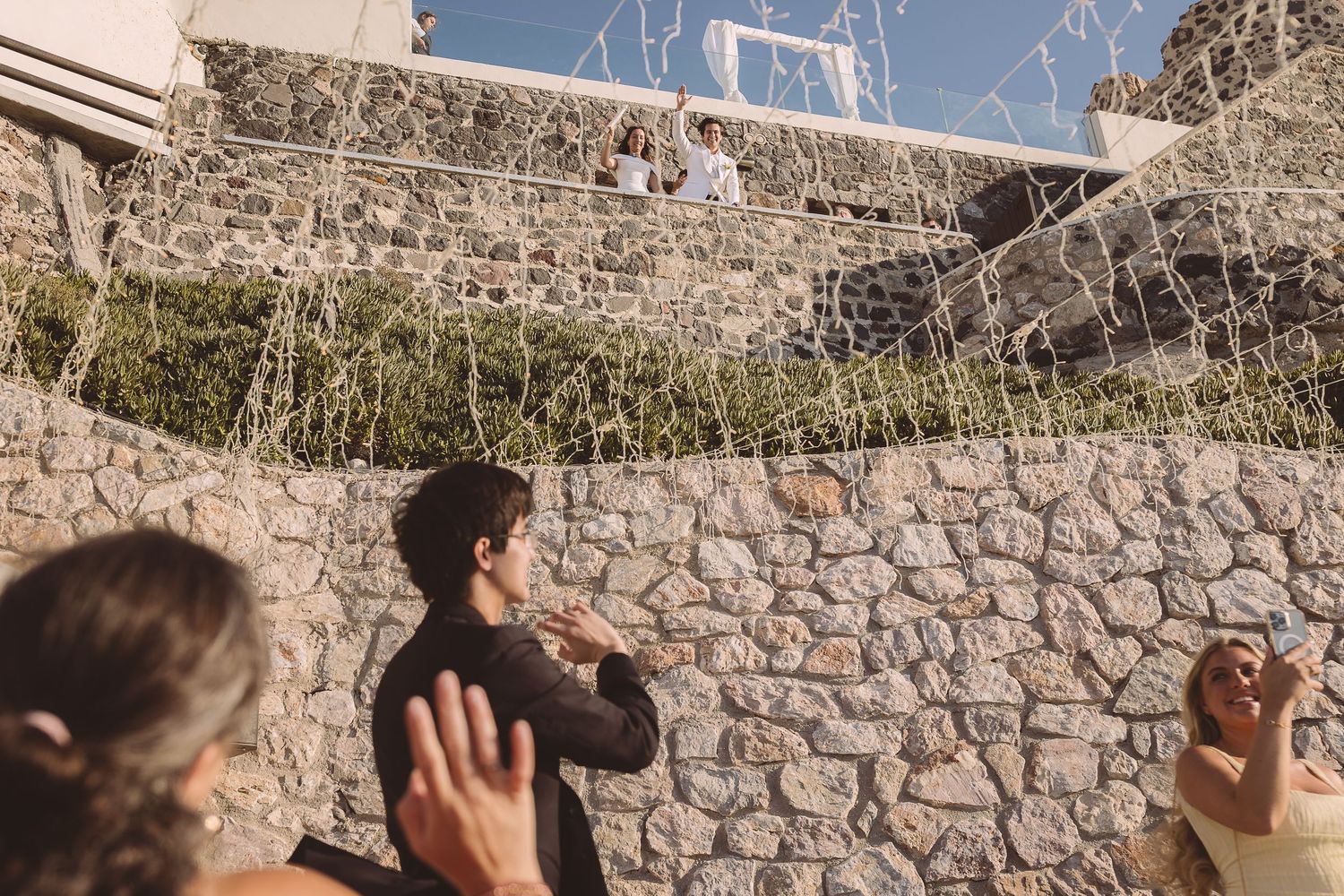 El Viento Santorini couple waving at guests over balcony at destination wedding.