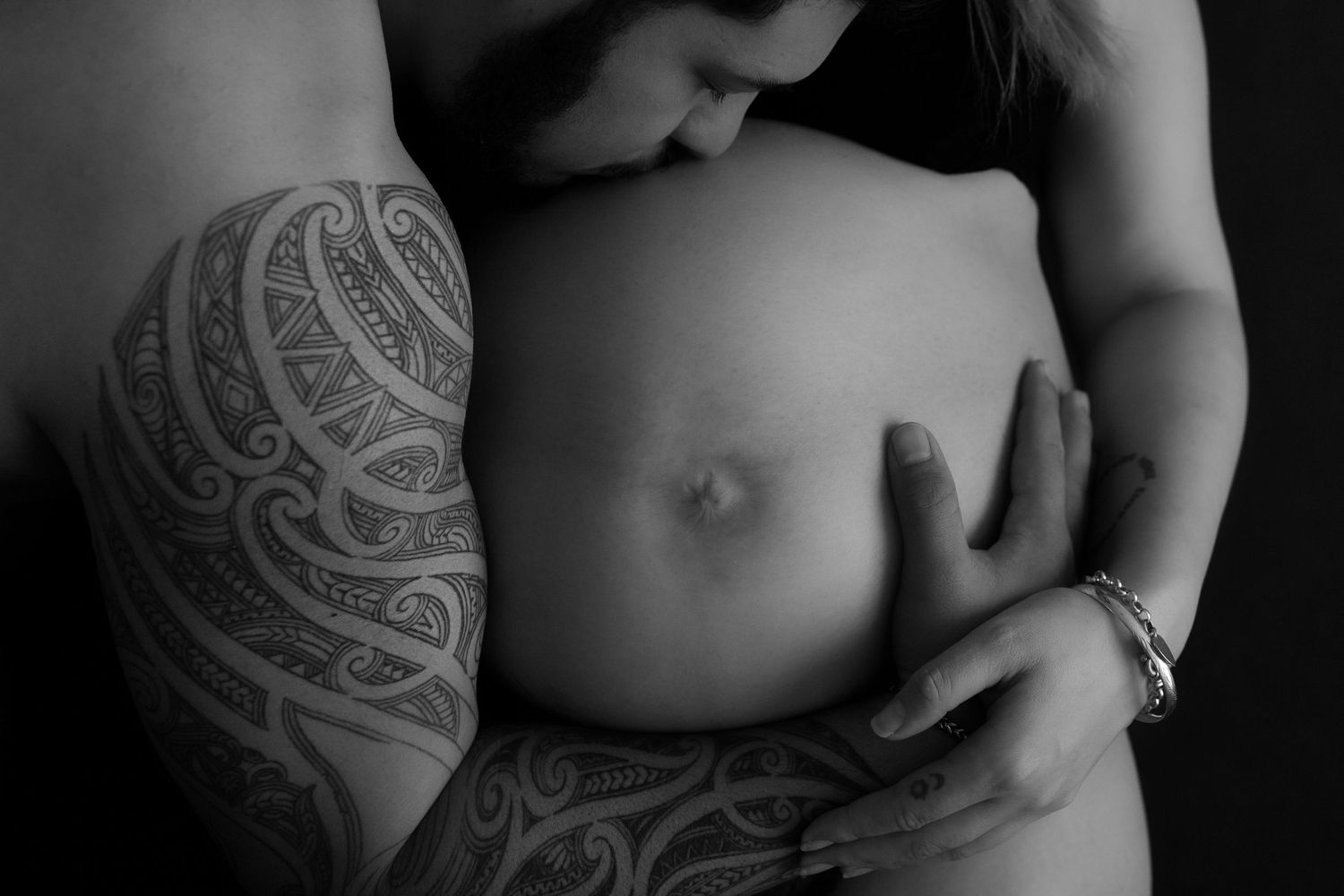 Black and white artistic maternity photo series showing a pregnant belly with intricate Maori designs.