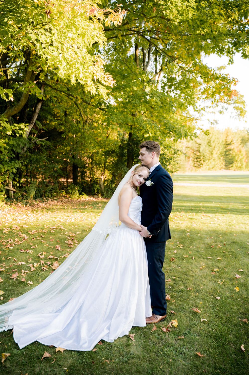 A romantic wedding photo series captured in a sun-drenched park with fall colors.