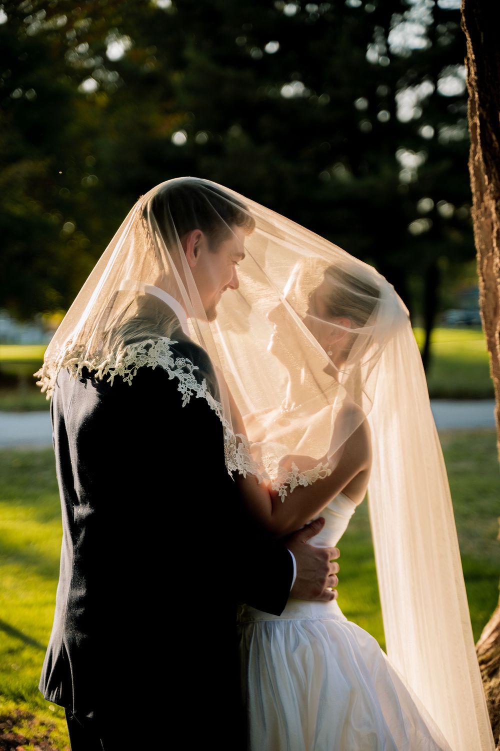 A romantic series of wedding photos showing silhouettes of a couple kissing under a flowing veil at sunset.