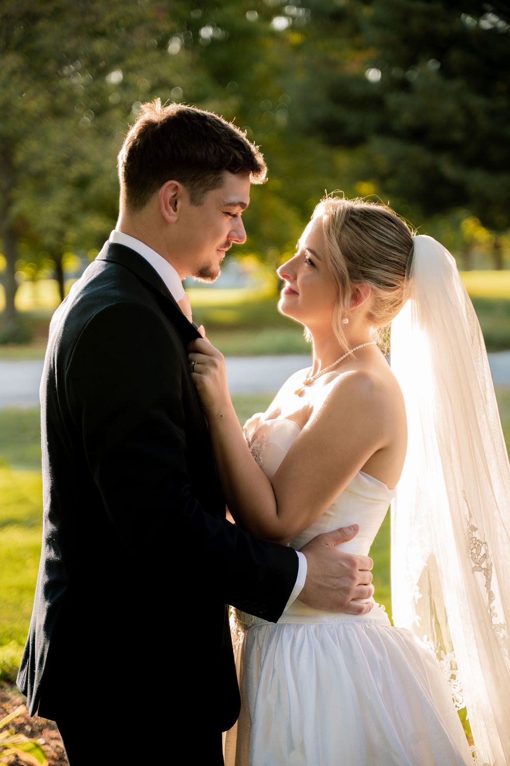 Romantic wedding couple shares intimate moments in golden sunlight during outdoor photo session.