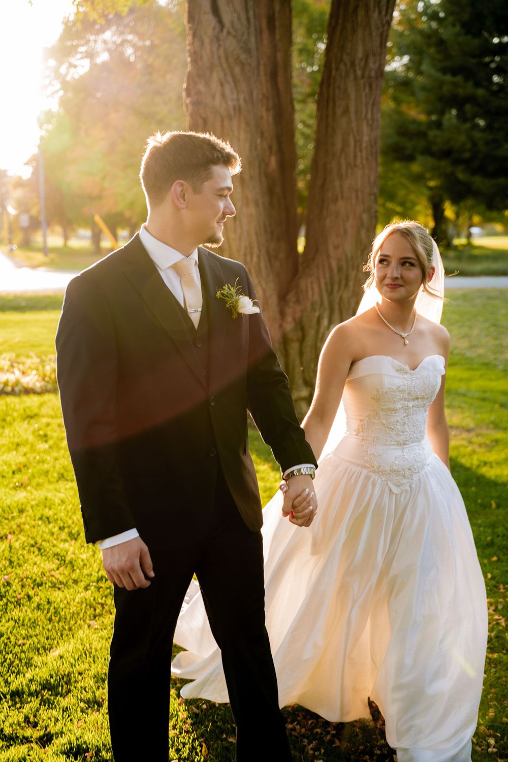 Newlyweds share tender moments during sunset photo session in a grassy field.