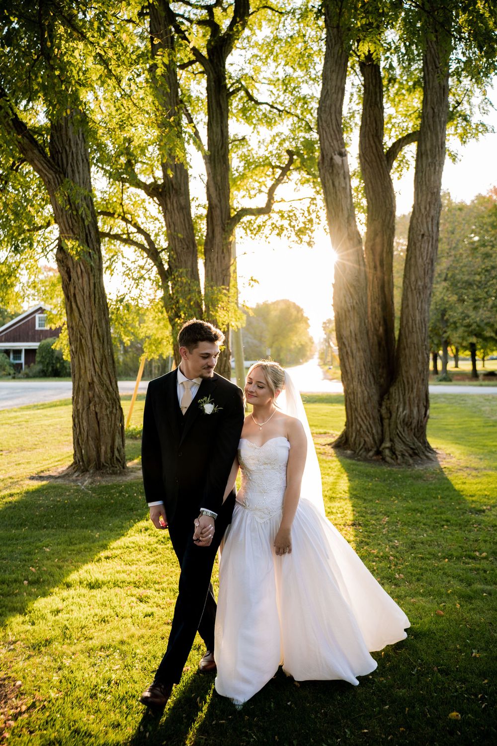 A couple walks along a tree-lined path at sunset, creating a romantic silhouette against the golden light.