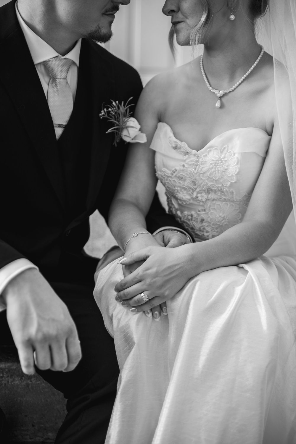 Black and white close-up photos of a bride and groom showing details of wedding attire and intimate moments.