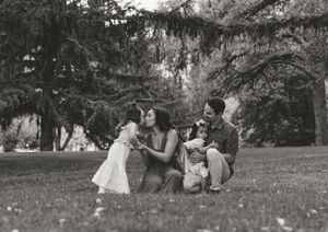 A vintage black and white photograph shows a family relaxing together on grass in a park setting.