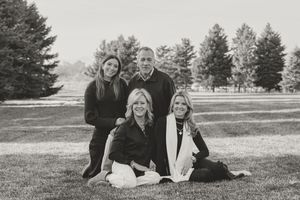 A series of black and white photographs showing a family group sitting together on grass with trees in the background.