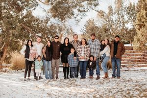Large group of people standing together in a row outdoors on a sunny winter day with snow on the ground.