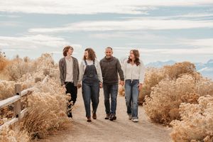 Group walking together on scenic coastal path with golden brush and blue sky in background.