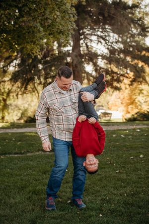 A playful moment captured in a grassy park at sunset with warm autumn lighting.