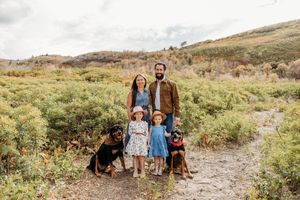 A group enjoys a scenic outdoor photoshoot on a mountain trail surrounded by wildflowers and natural terrain.