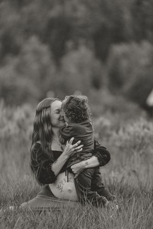 A romantic black and white photo series showing a couple lying in a grassy meadow sharing intimate moments together.