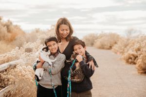 Family enjoying tender moments together while sitting on a path surrounded by golden autumn foliage.