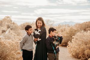 Family enjoying a candid moment together during an outdoor autumn photoshoot in a golden field at sunset.