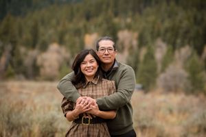 A couple shares intimate moments during an outdoor photoshoot in a rustic autumn setting.