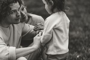 A tender black and white moment between parent and child sitting together outdoors.