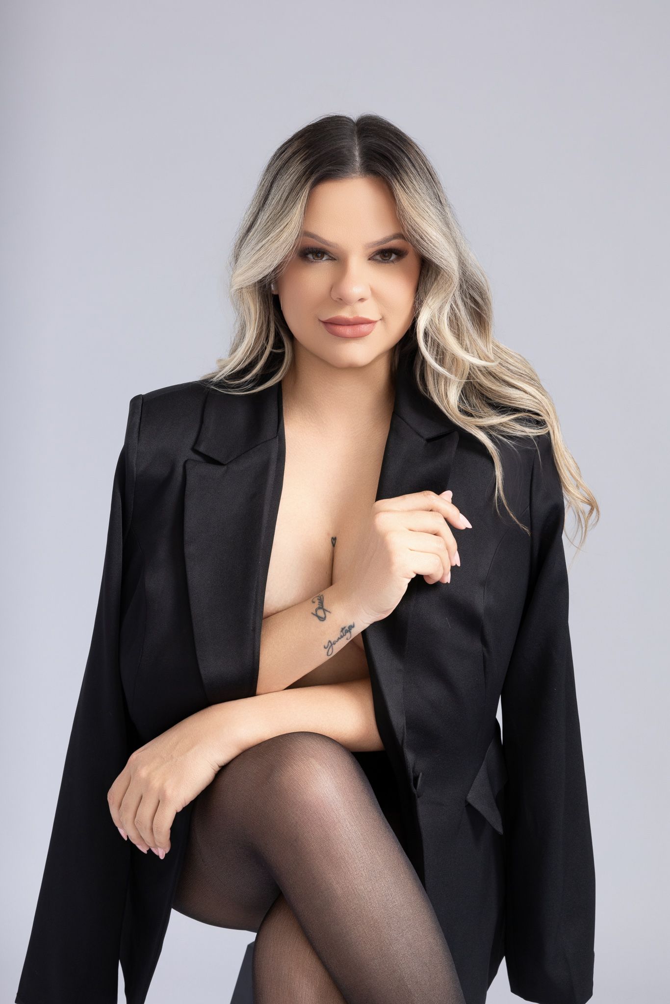 Professional fashion photo series featuring a black blazer and blonde hair against a gray studio backdrop.