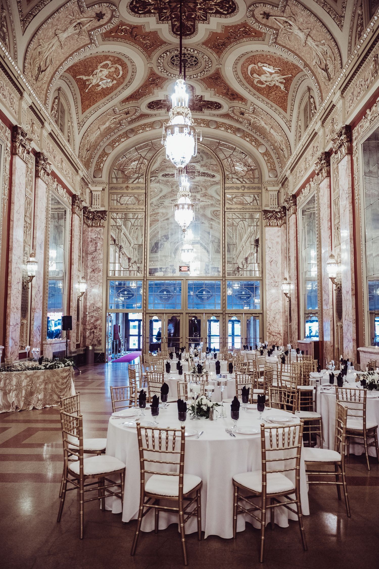 Ballroom with crystal chandeliers, mirrored walls, and elegant table settings for a wedding at the Rialto Square Theatre.