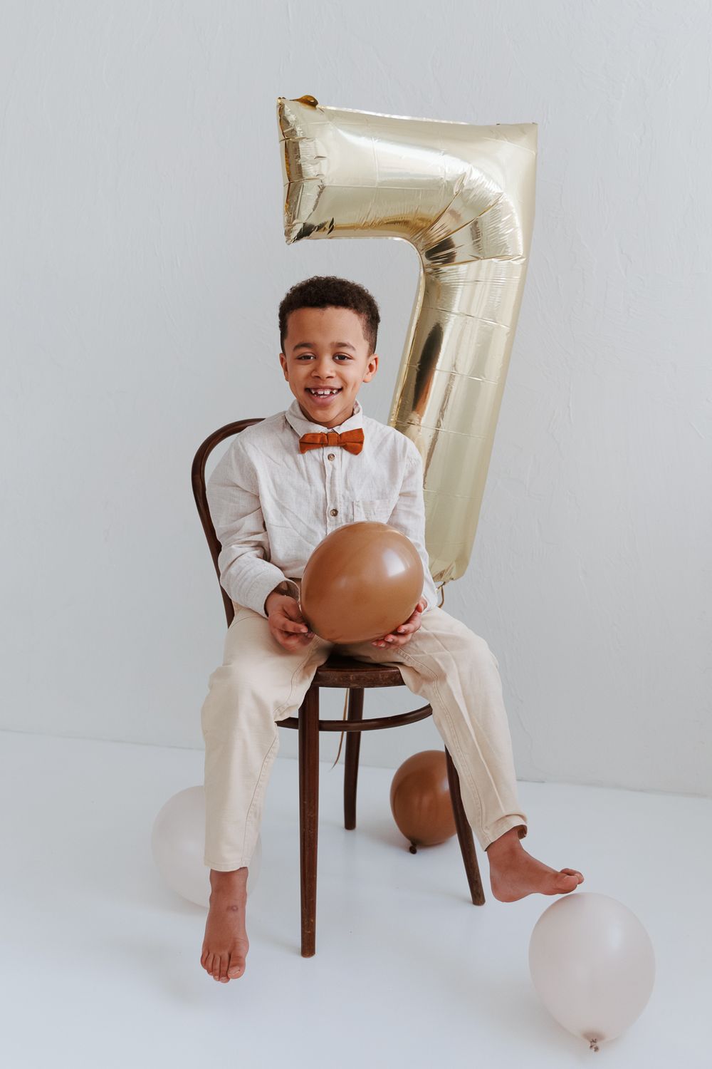 Lapsi istuu studiotuolilla ja katsoo hymyillen kameraan – lapsen muotokuvaus Helsingissä.