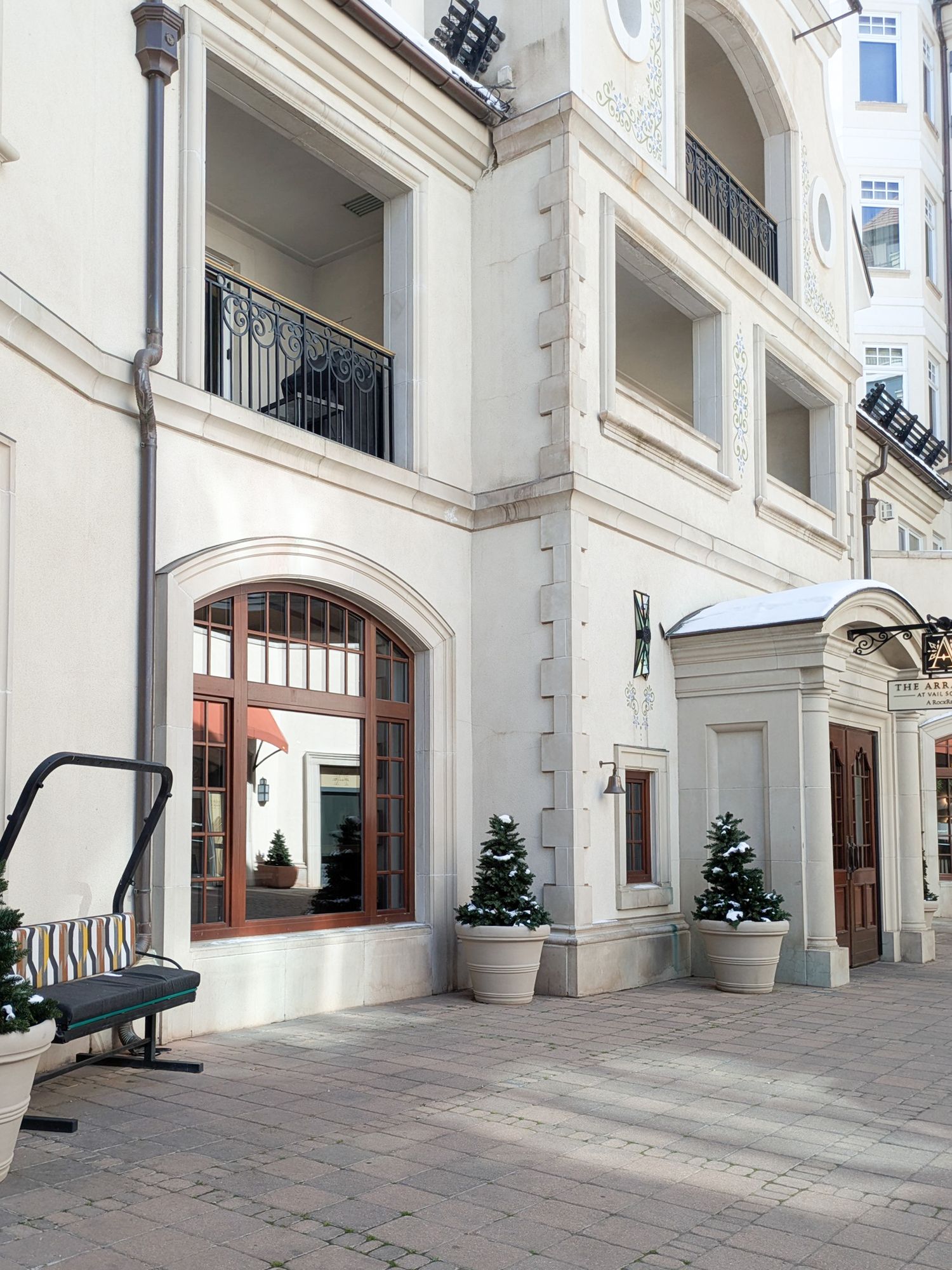 Elegant white arched colonnade hallway with decorative trim and small potted trees lining the interior walkway.