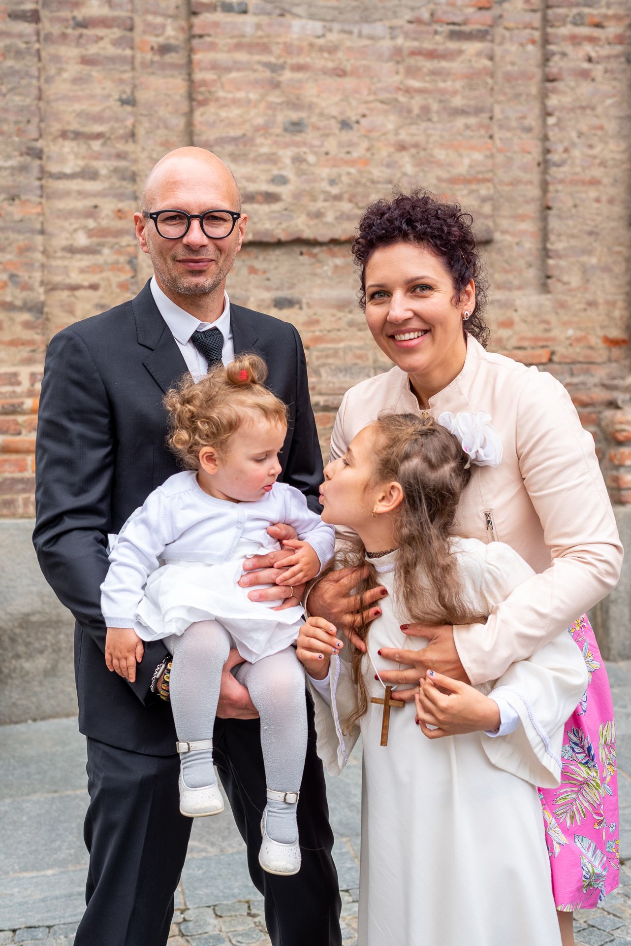 Family portrait outside brick church after religious ceremony.