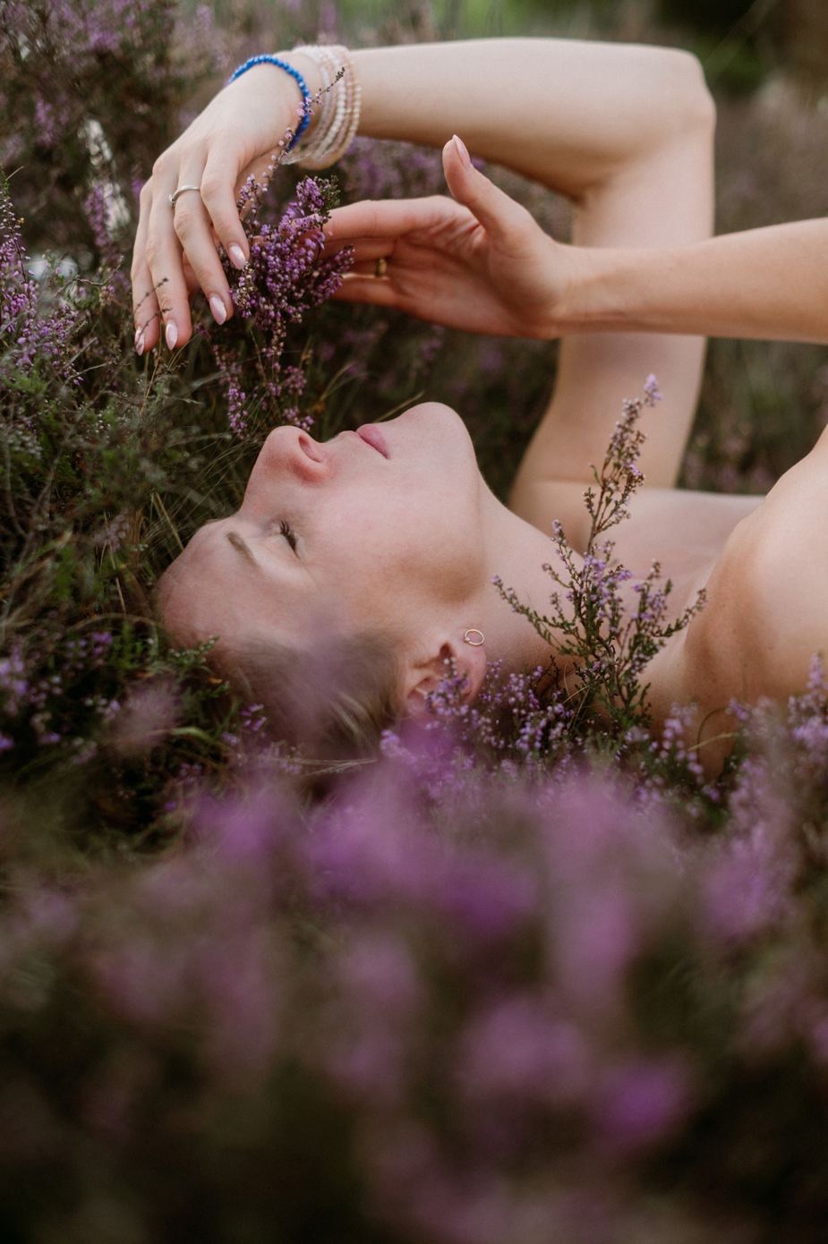 Artistic portrait series showing hands gracefully posed among blooming purple heather flowers in soft natural light.