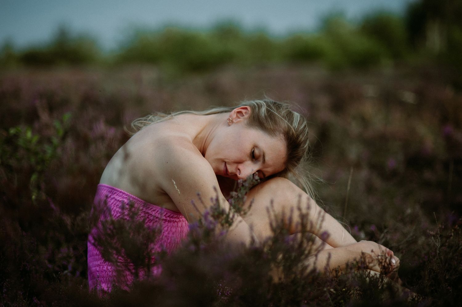 Dreamy portrait in a purple wildflower field with soft natural lighting and moody atmosphere.