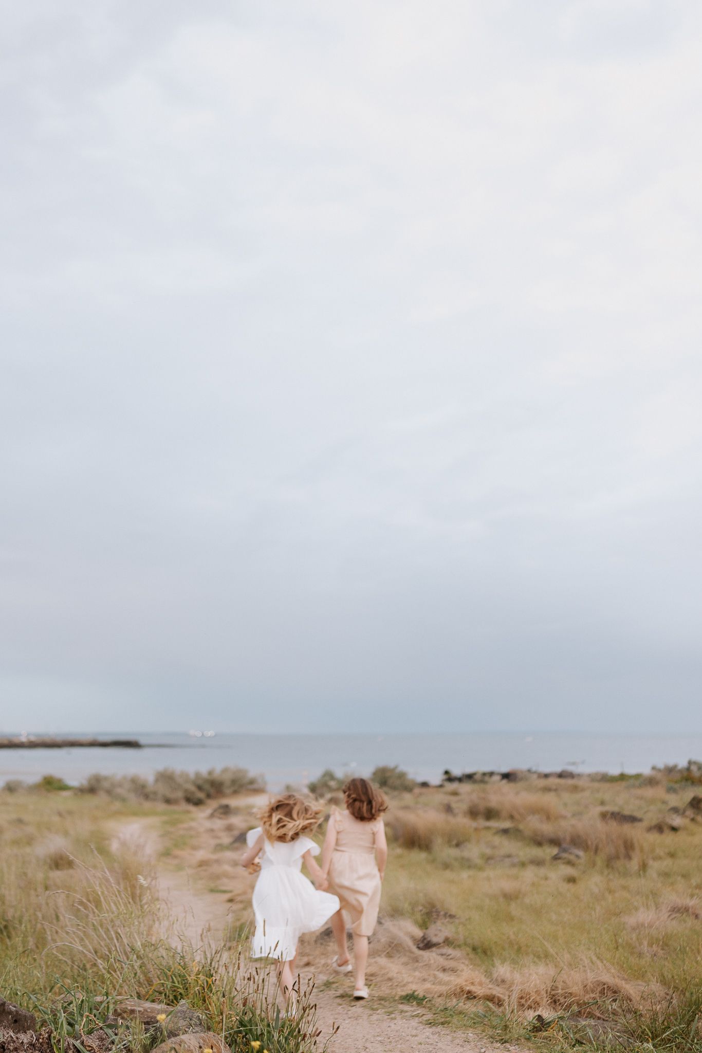 A family poses together near a rustic barn in a golden field at sunset.