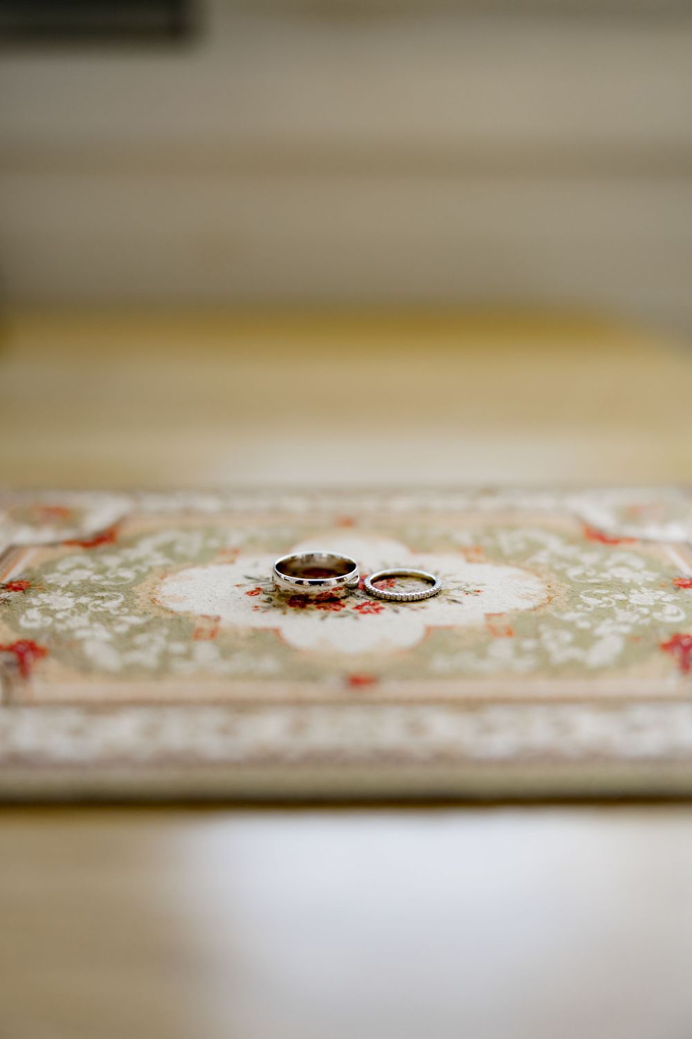 Wedding rings displayed on an ornate patterned surface with delicate floral details.