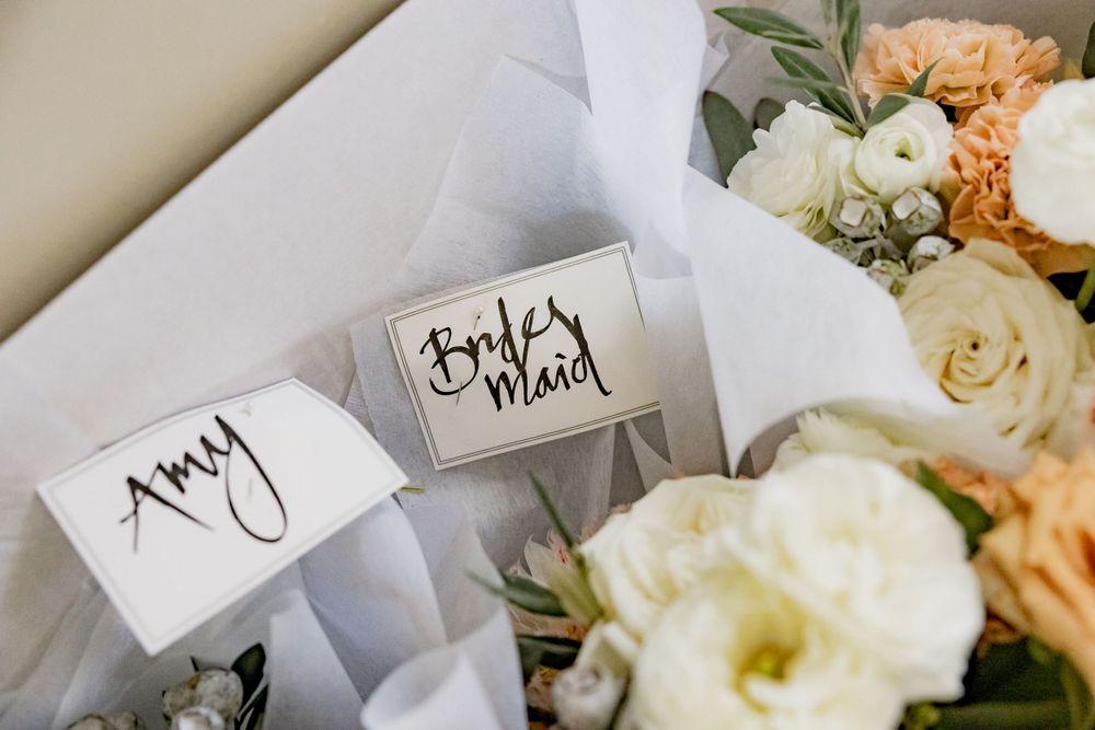 Wedding place cards with floral arrangements in white and peach colors.