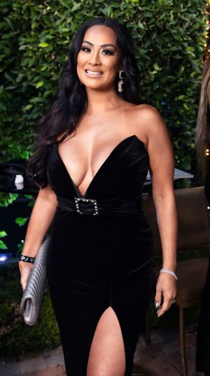 A black velvet evening gown with a deep V-neckline and thigh slit is showcased at an event.