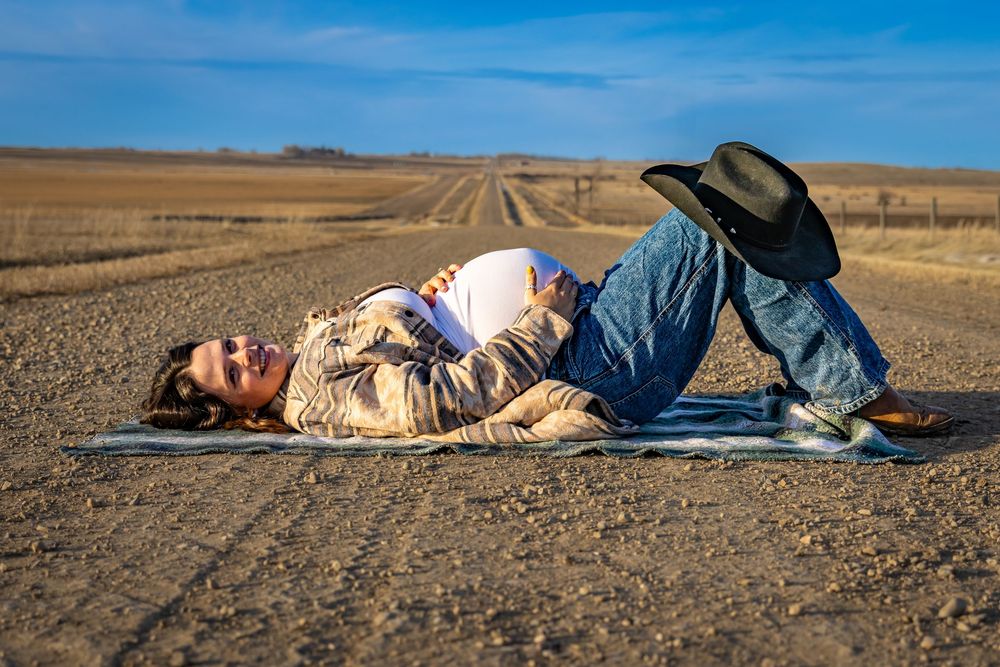 a pregnant woman on a dirt road showing her baby bump.