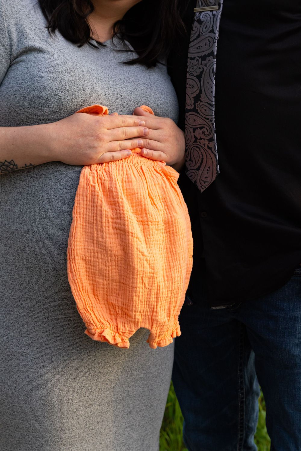 a pregnant holds a baby onesie.
