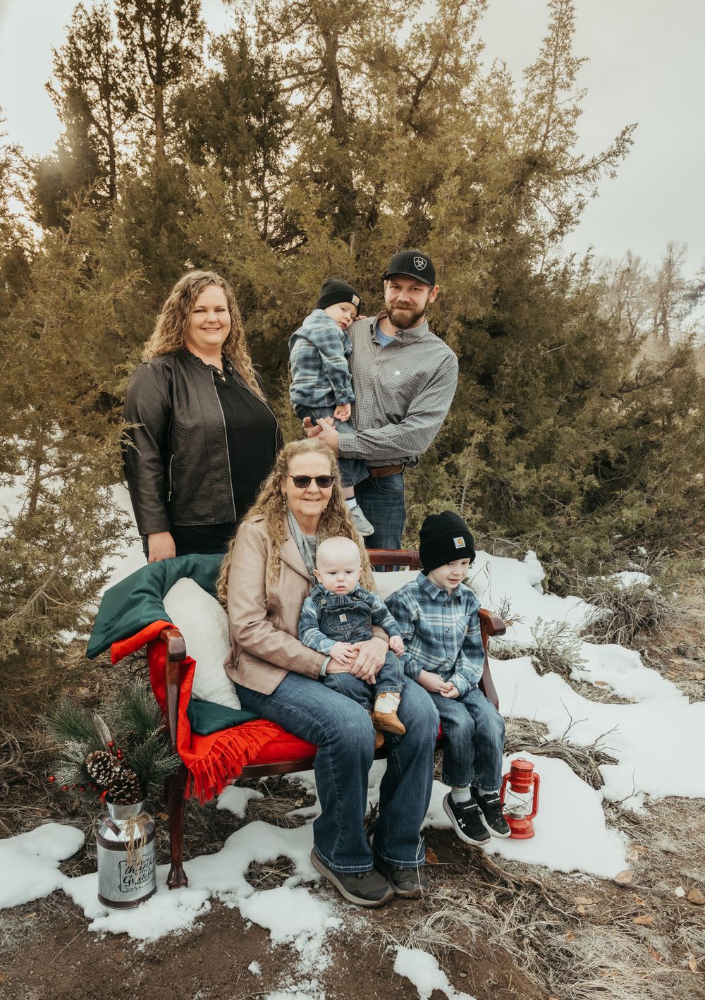 A casual winter family portrait session in the snow with evergreen trees.