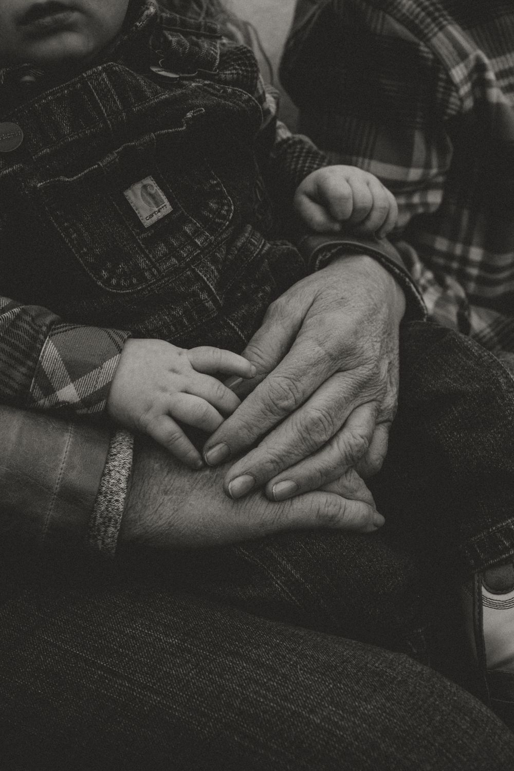 Close-up black and white photo of hands resting on denim jeans.