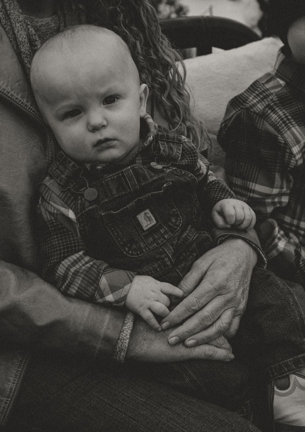 Black and white close-up portrait showing hands and denim clothing details.
