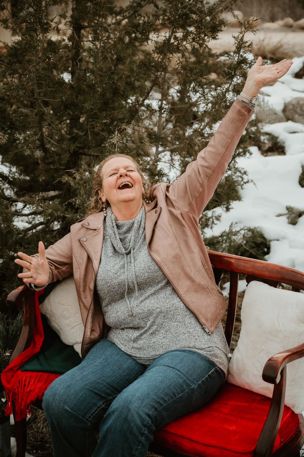 Candid moment of joy and laughter on a red couch in a snowy outdoor setting.