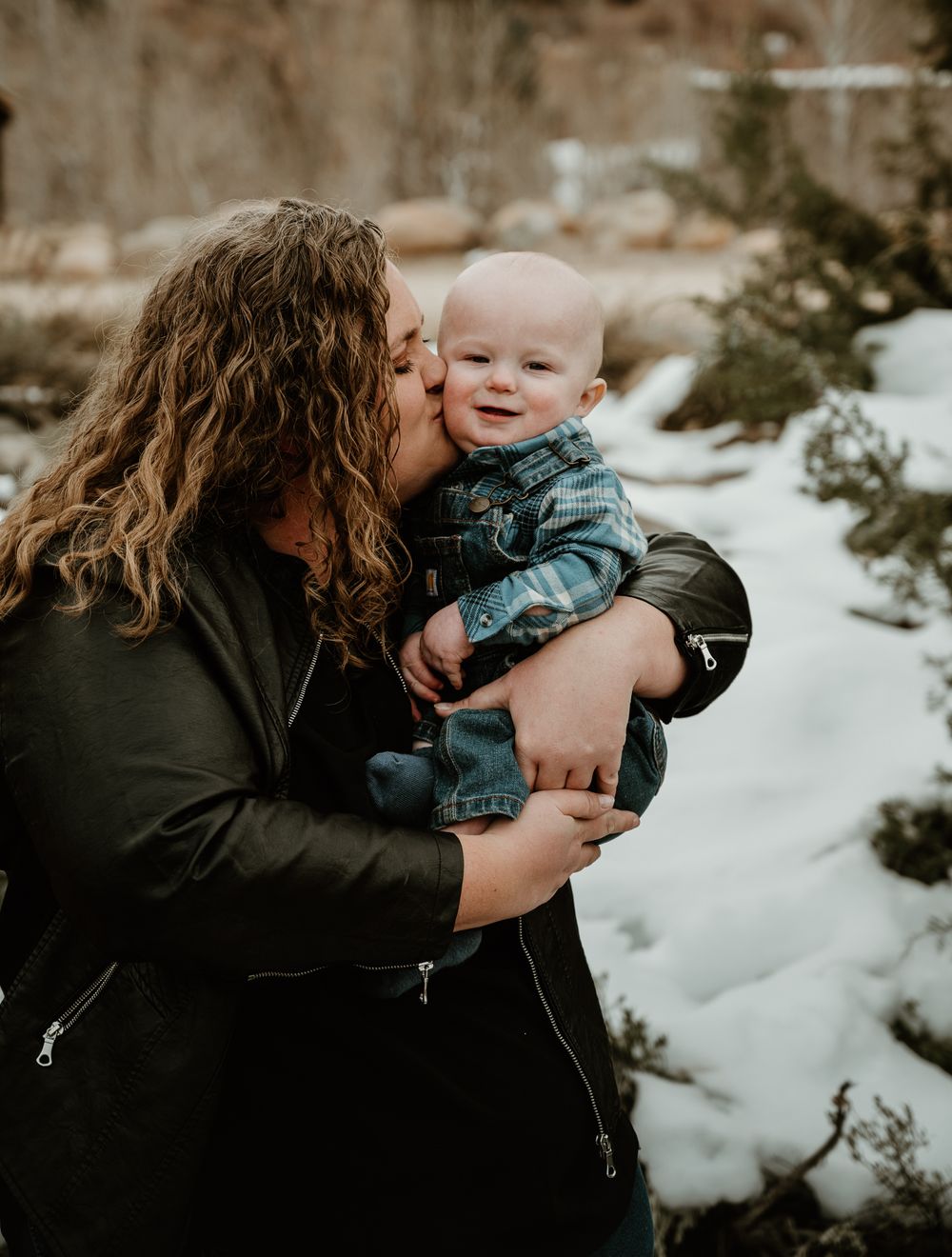 A tender family moment captured in a snowy winter setting with warm embraces and joyful expressions.