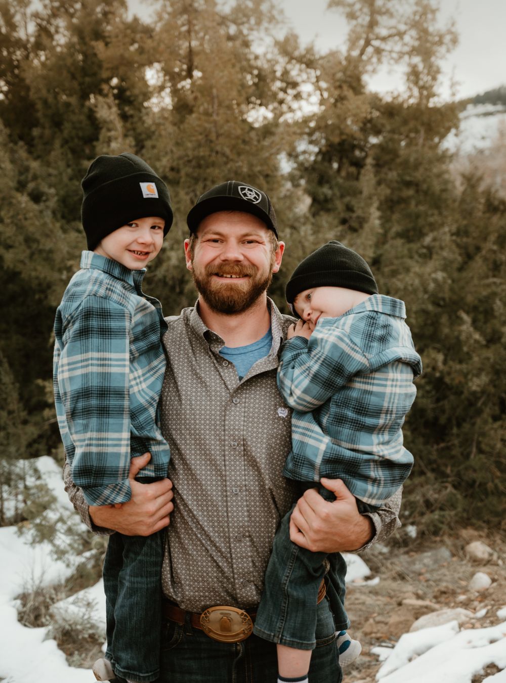 A heartwarming outdoor family portrait in matching plaid shirts against a natural backdrop.