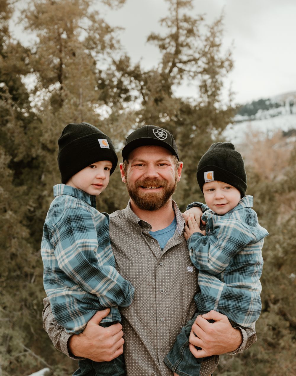 Family members wearing winter hats and plaid shirts share happy moments in a snowy outdoor setting.