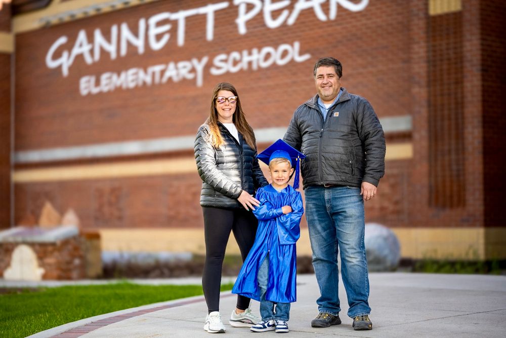 Gannett Peak Elementary School sign with graduate in blue cap and gown.