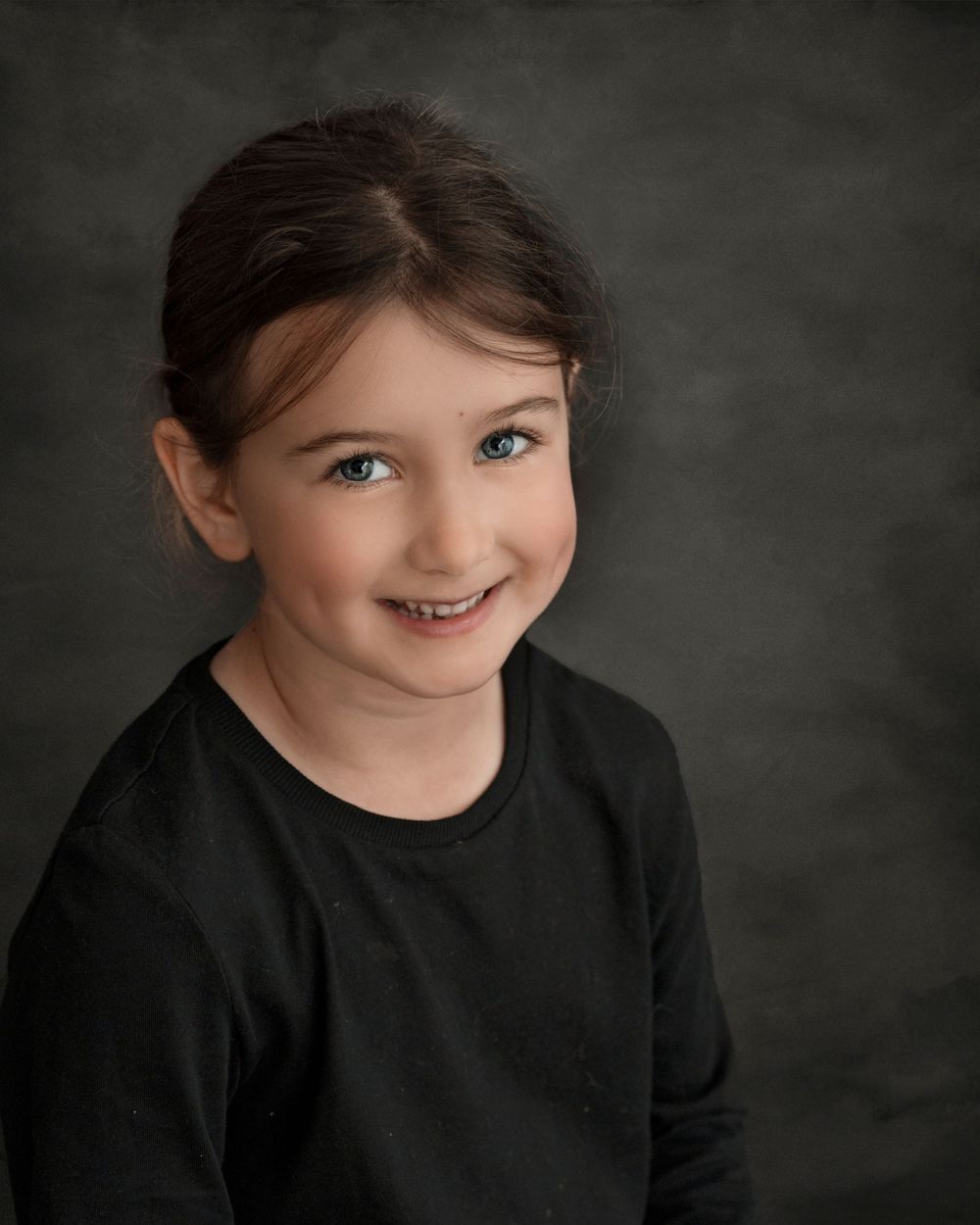 Studio portrait showing a girl wearing black on a dark background