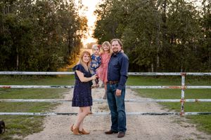 family of four standing in front of farm gate