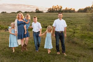 parents walking pasture with four kids