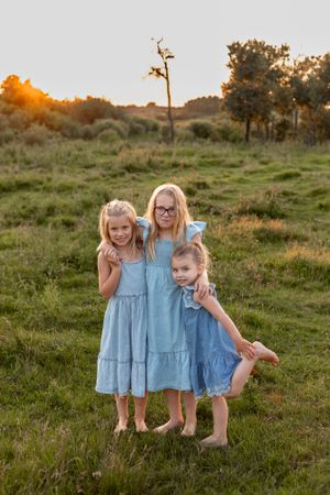 sisters matching in blue dresses in cow pasture