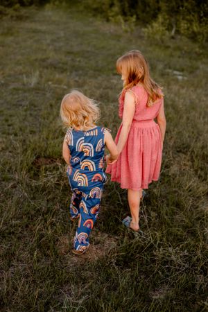sisters holding hands walking through field