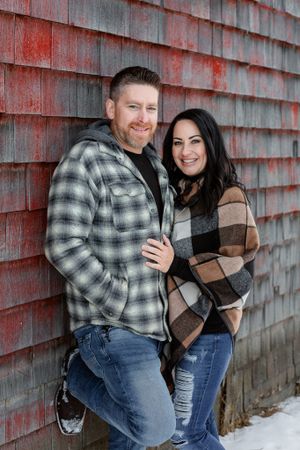 couple poses in front of barn