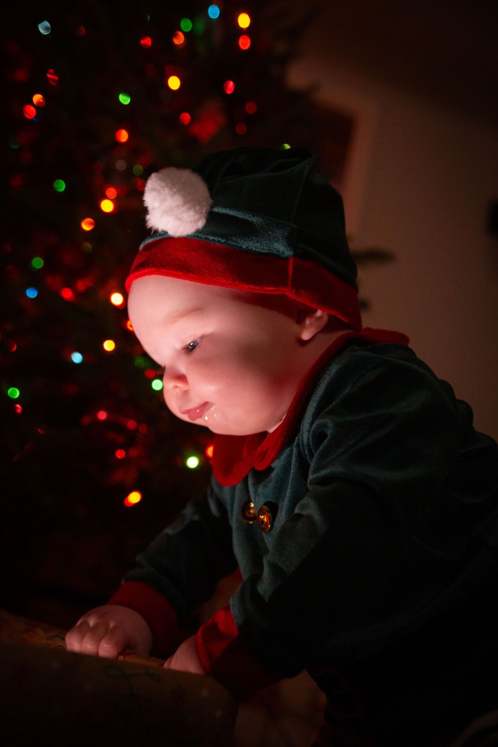 Silhouette against Christmas tree lights wearing dark clothing and winter hat.