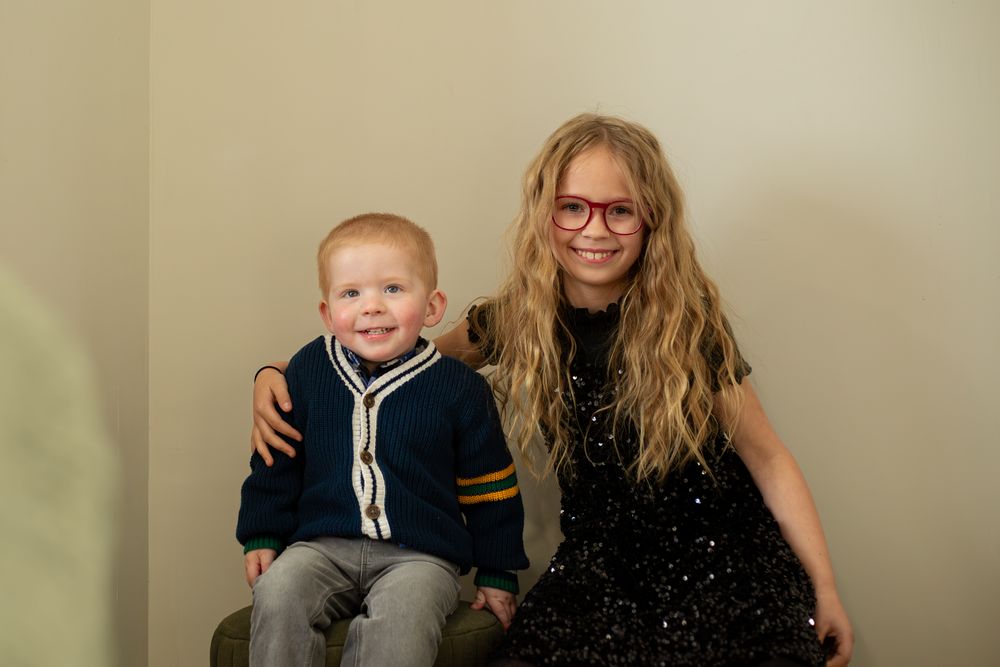 Two people pose together on a green ottoman during Christmas photos.